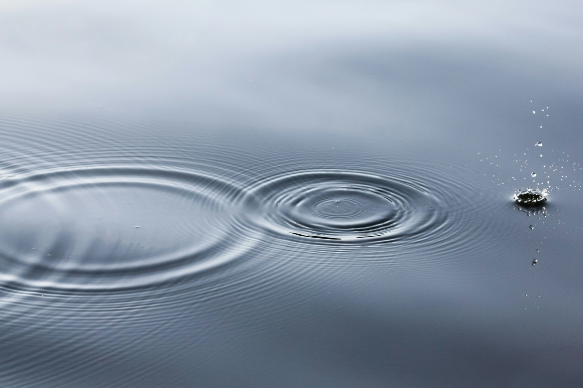Water surface with ripples and droplets creating circular waves.
